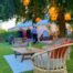 Garden table and chairs outside the marquee beside a tree that holds lanterns.